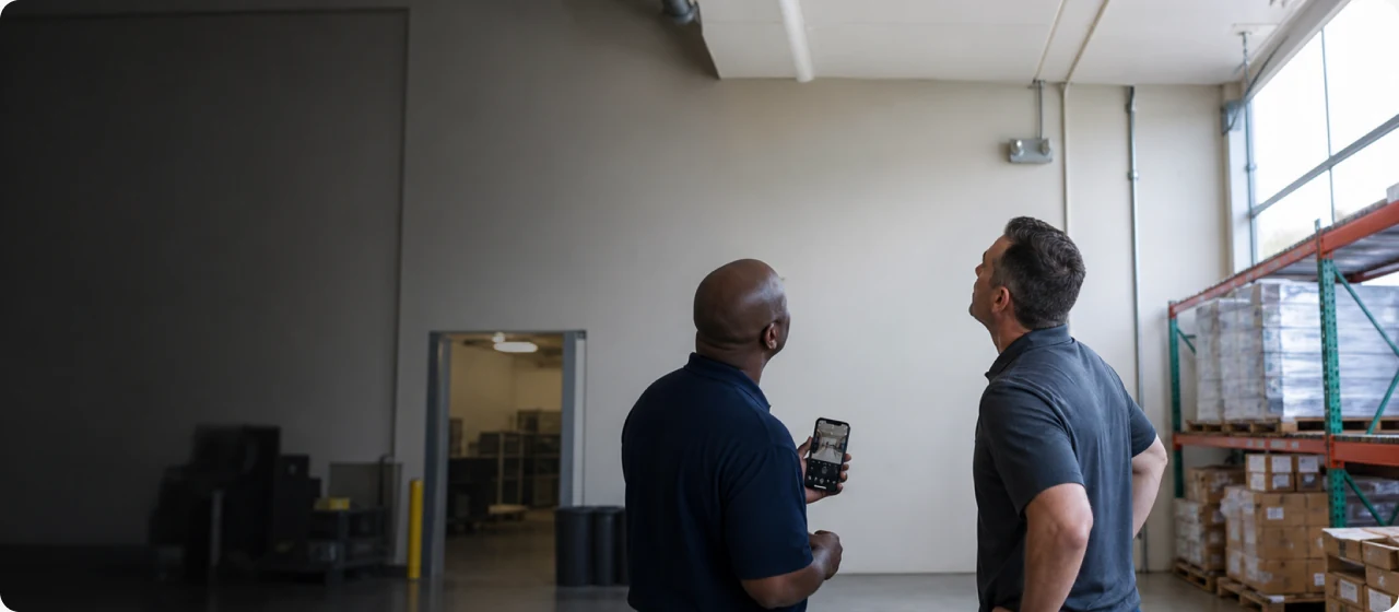 Two people examining the ceiling inside a commercial building.