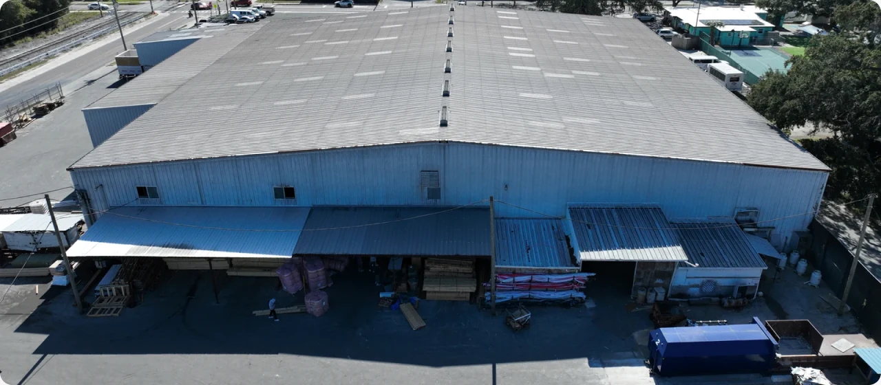 Aerial view of a warehouse with a broad low-slope roof.
