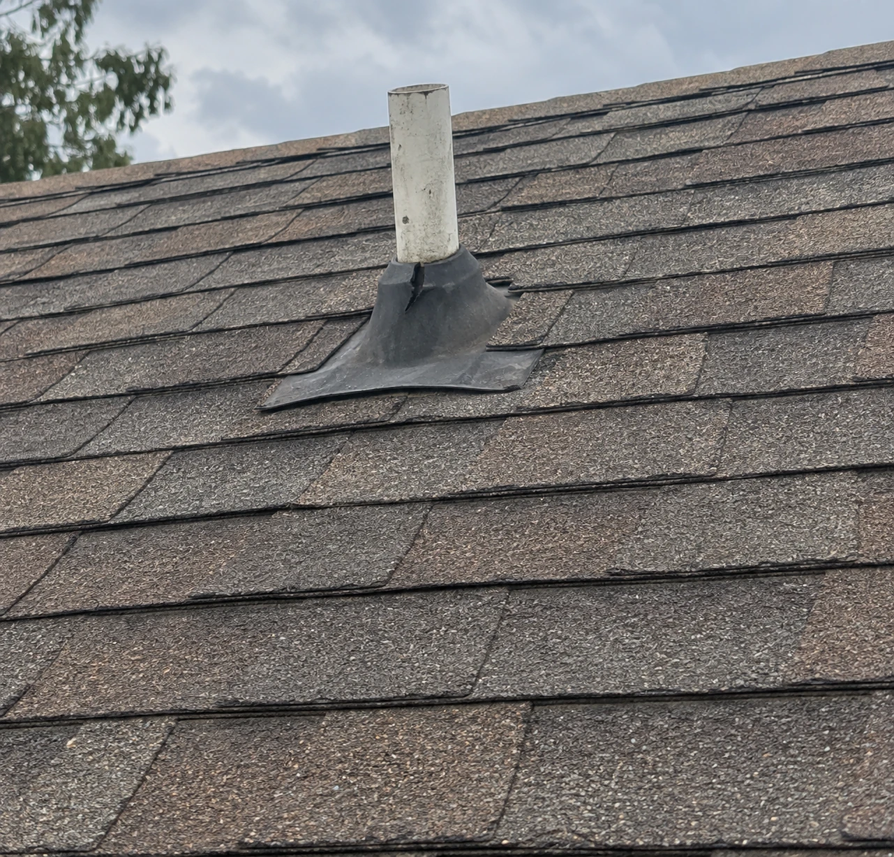 Roof vent and flashing surrounded by shingles.