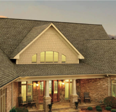 Front view of a house with a steep shingle roof and a covered porch.