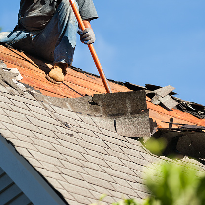 Roofing worker installing shingles on a sloped roof.
