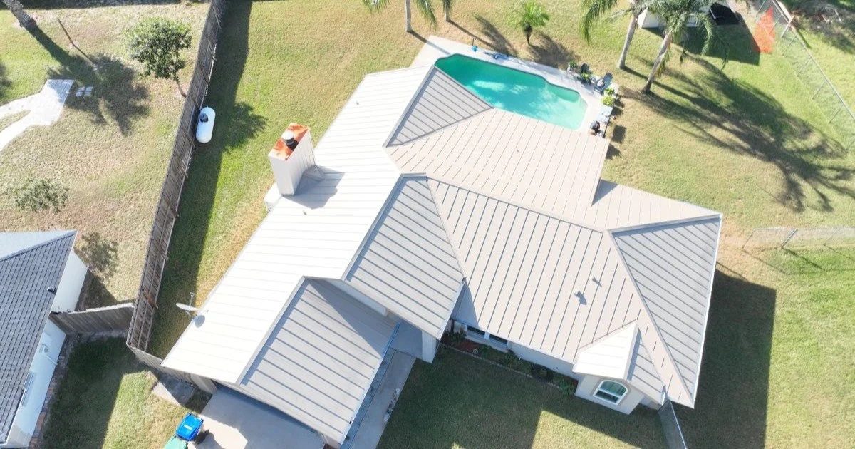 Aerial view of a house with a light-colored metal roof.