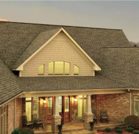 Front view of a house with a steep shingle roof and a covered porch.